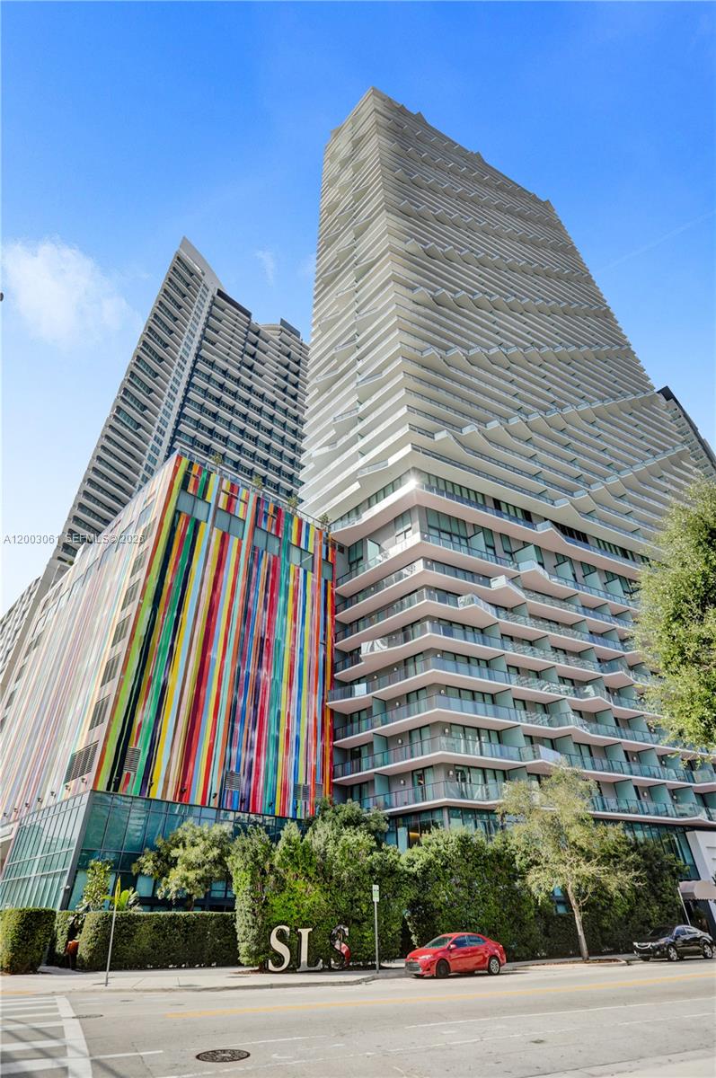 A low-angle exterior view of a modern high-rise building with a colorful, striped facade — 1300 S Miami Ave # 3111, Miami FL 33130, MIAMI, FL