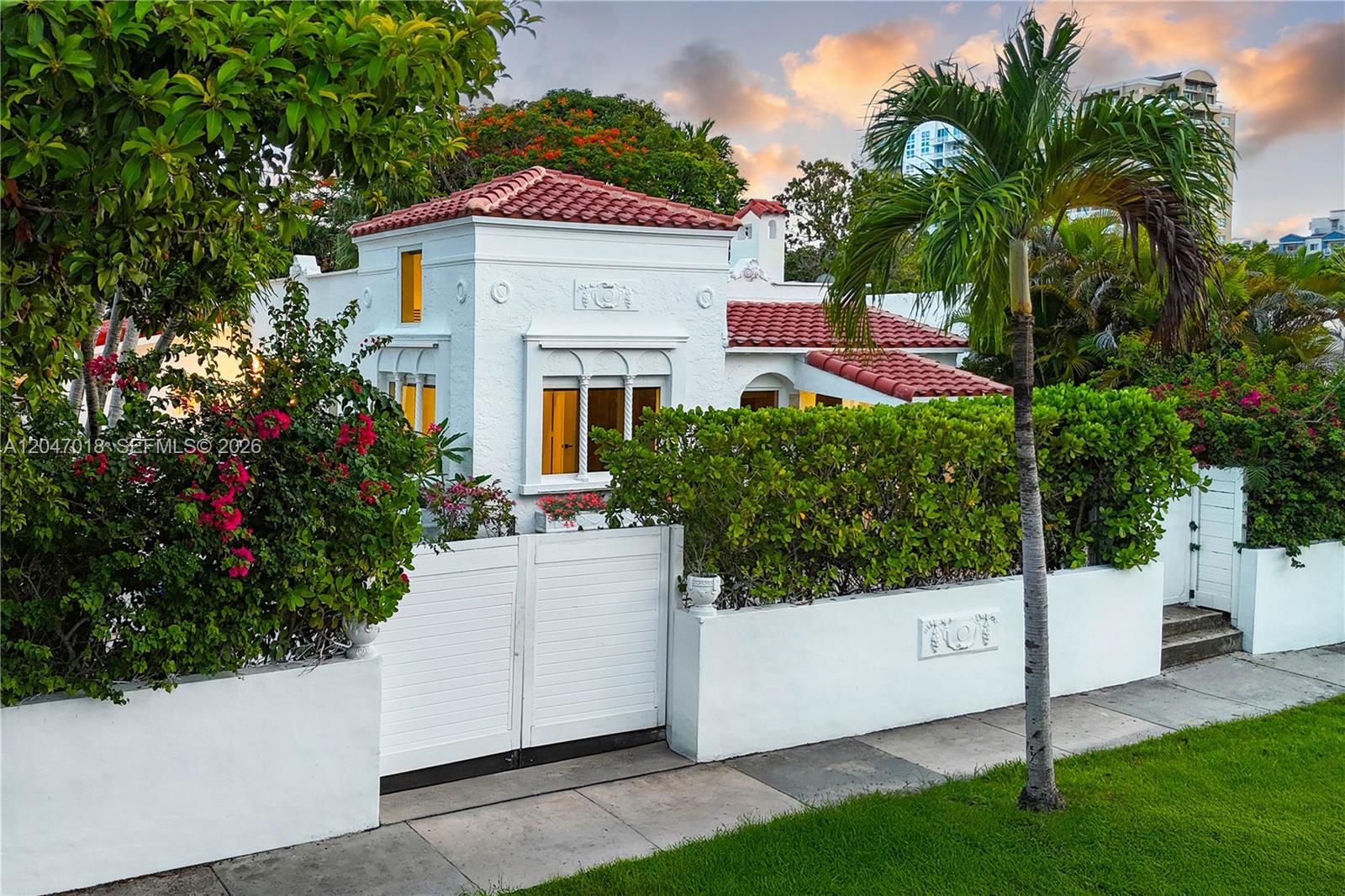 A white Mediterranean-style house with a red tile roof sits behind a gated privacy wall — 3616 SW 26th St, Miami FL 33133, MIAMI, FL
