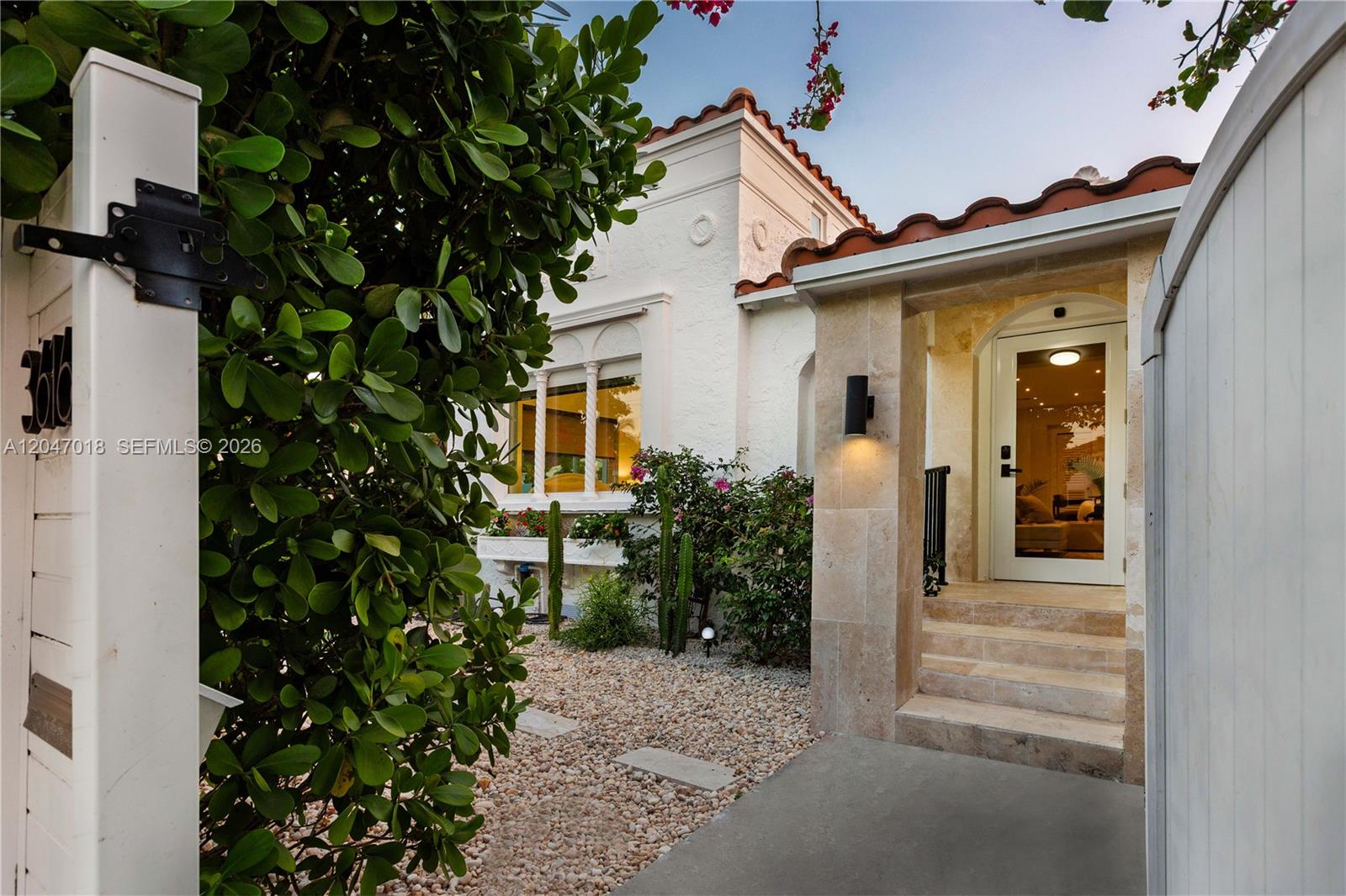 A white stucco house with a tiled roof features a stone-tiled entryway and gravel landscaping — 3616 SW 26th St, Miami FL 33133, MIAMI, FL