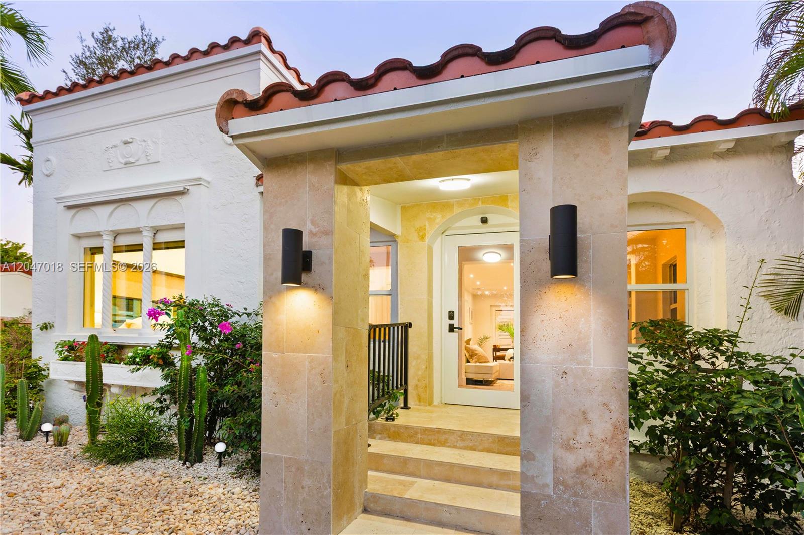 The exterior of a white stucco house features a stone-tiled entryway with two wall-mounted lights — 3616 SW 26th St, Miami FL 33133, MIAMI, FL