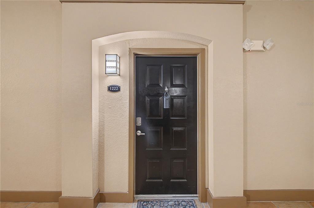 A black front door with a silver handle and a room number plaque is shown — 4221 W SPRUCE STREET UNIT 1222, TAMPA, FL