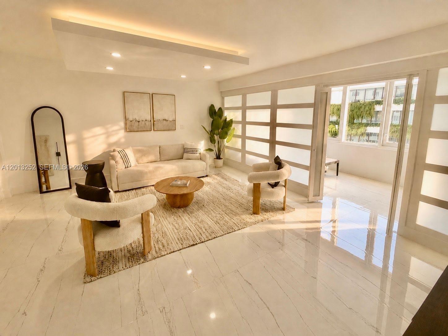A bright living room features white tile floors, a neutral sofa, and glass-paneled doors — 2301 Collins Ave # 628, Miami Beach FL 33139, MIAMI BEACH, FL