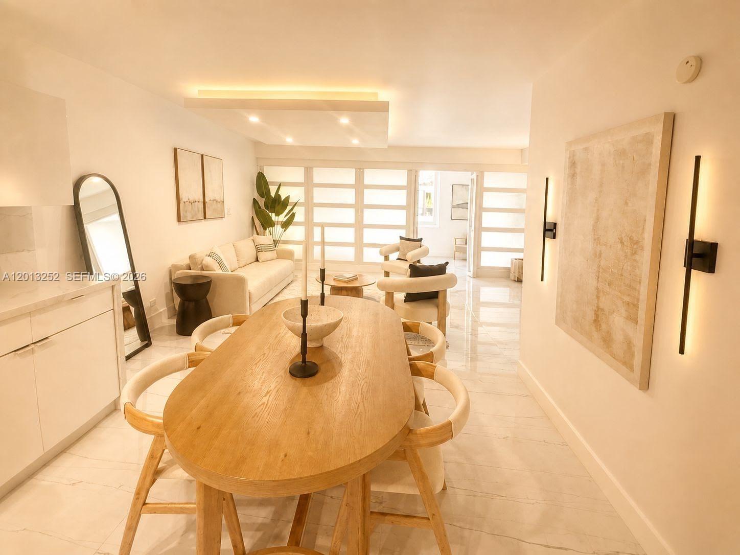 A dining area with a wooden table and chairs sits in front of a living room — 2301 Collins Ave # 628, Miami Beach FL 33139, MIAMI BEACH, FL