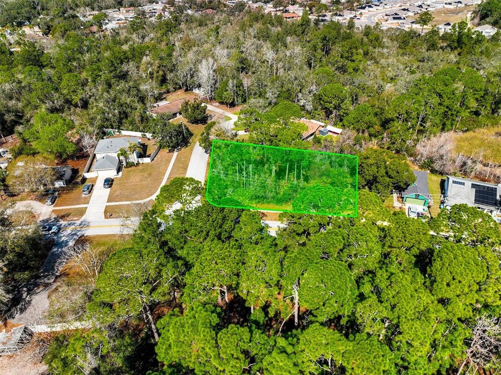 An aerial view shows a rectangular, wooded vacant lot outlined in green near a road — 632 ANDERSON DRIVE, DELTONA, FL