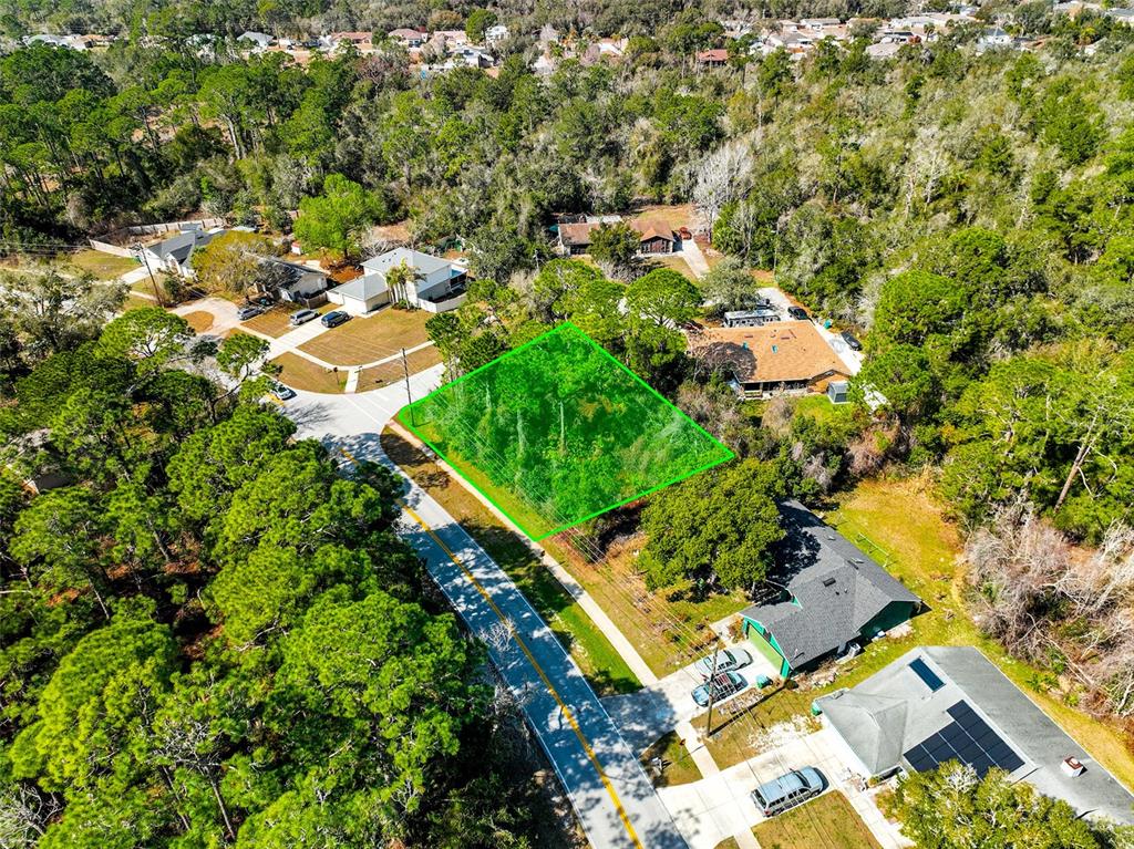 An aerial view shows a vacant, wooded residential lot highlighted in green next to houses — 632 ANDERSON DRIVE, DELTONA, FL