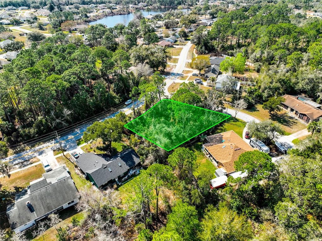 An aerial view shows a vacant, wooded lot highlighted in green between two residential houses — 632 ANDERSON DRIVE, DELTONA, FL
