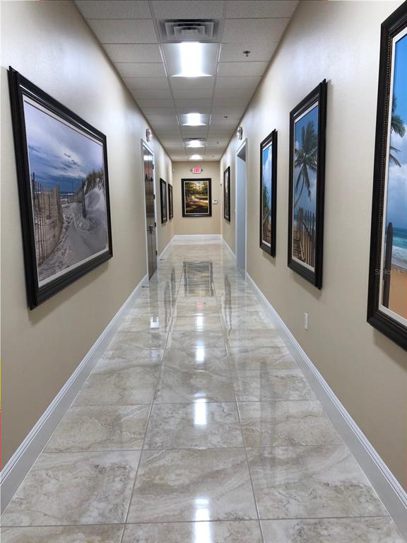 A long hallway with beige walls, tiled floors, and framed artwork on both sides — 350 ANCHOR ROAD ROAD UNIT 1040, CASSELBERRY, FL