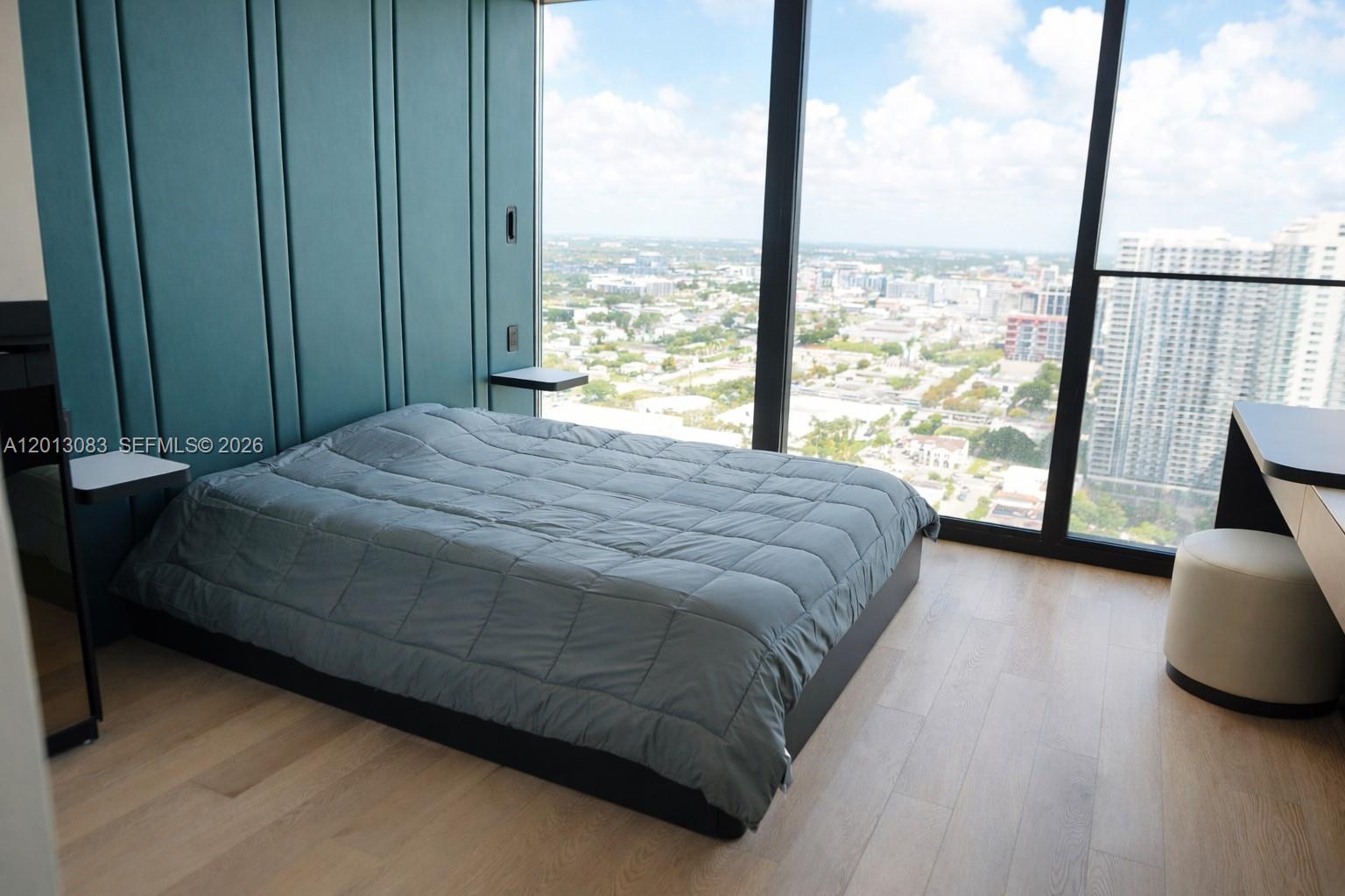 A bedroom features a bed against a teal paneled wall with floor-to-ceiling city views — 20 NE 11 st # 3403B, Miami FL 33132, MIAMI, FL