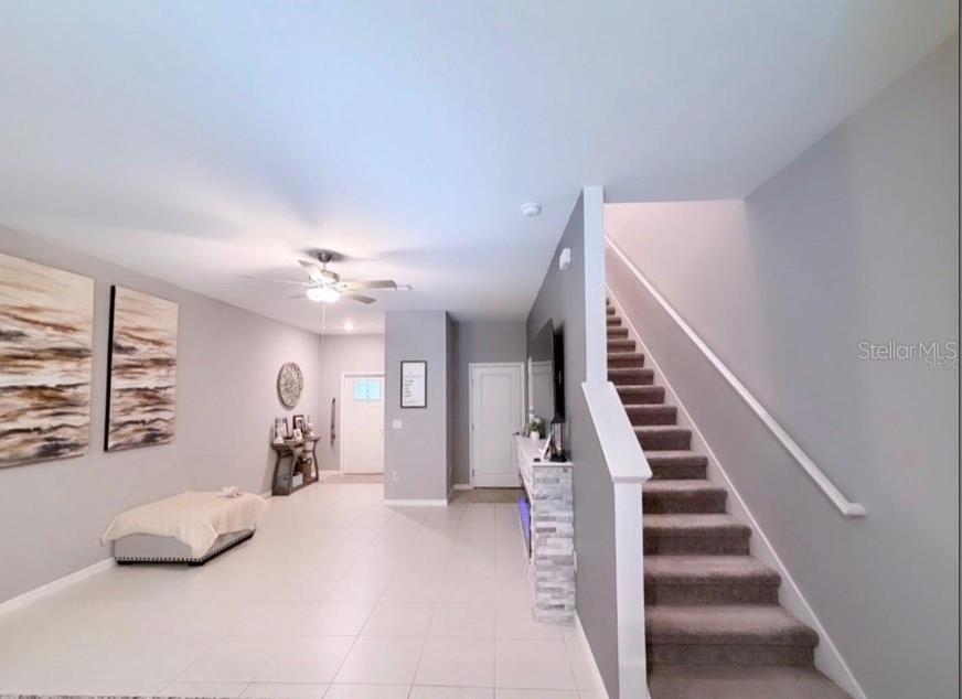 A living room with light tile flooring, a carpeted staircase, and a stone-accented fireplace — 6047 ACARA LANE, LAND O LAKES, FL