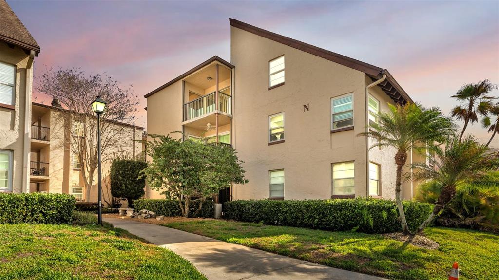 A three-story apartment building with beige stucco exterior and a walkway in the foreground — 2025 SYLVESTER ROAD UNIT N101, LAKELAND, FL