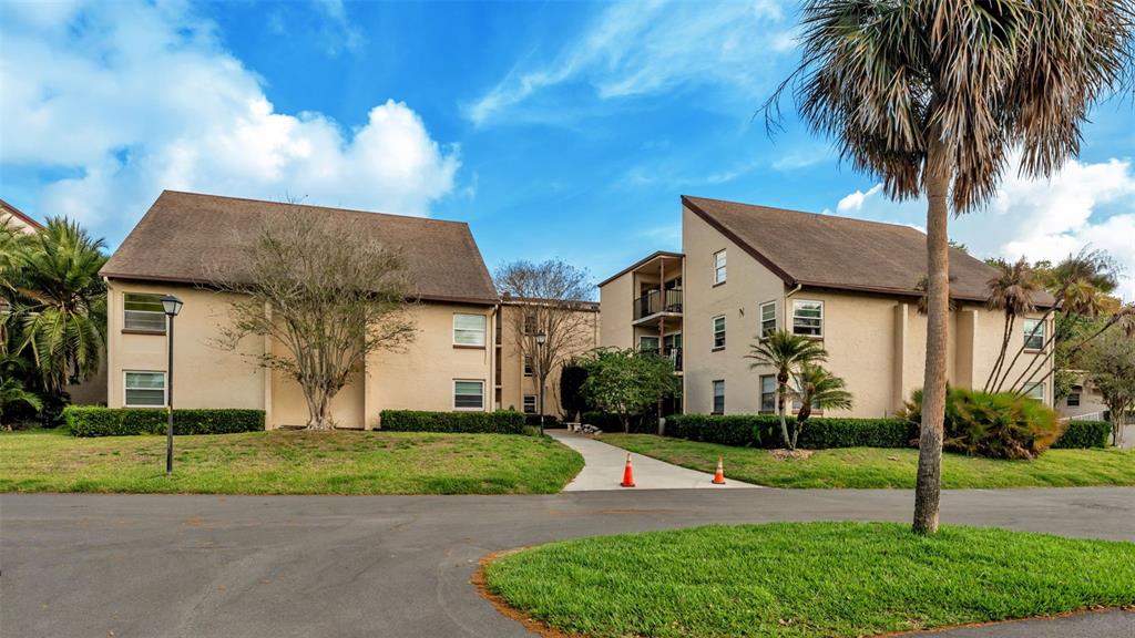 A two-story apartment building with tan stucco walls and a brown shingled roof — 2025 SYLVESTER ROAD UNIT N101, LAKELAND, FL