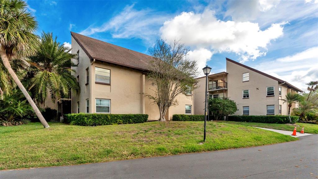 Two multi-story apartment buildings with beige stucco exteriors sit on a grassy lawn — 2025 SYLVESTER ROAD UNIT N101, LAKELAND, FL
