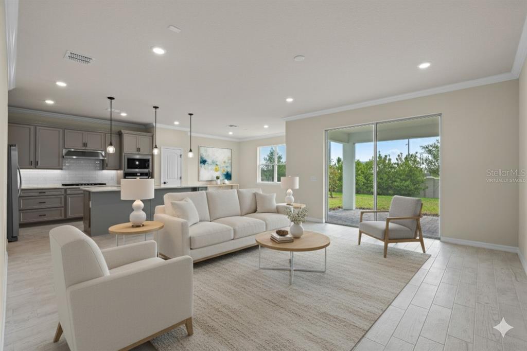 This virtually staged living room features light tile floors, a neutral sofa, and sliding doors — 10245 PARK ESTATES AVENUE, ORLANDO, FL