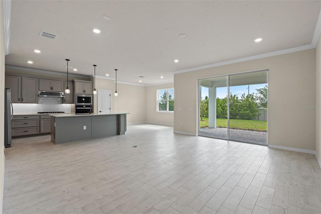 A kitchen with gray cabinets and an island opens to a living area with tile floors — 10245 PARK ESTATES AVENUE, ORLANDO, FL