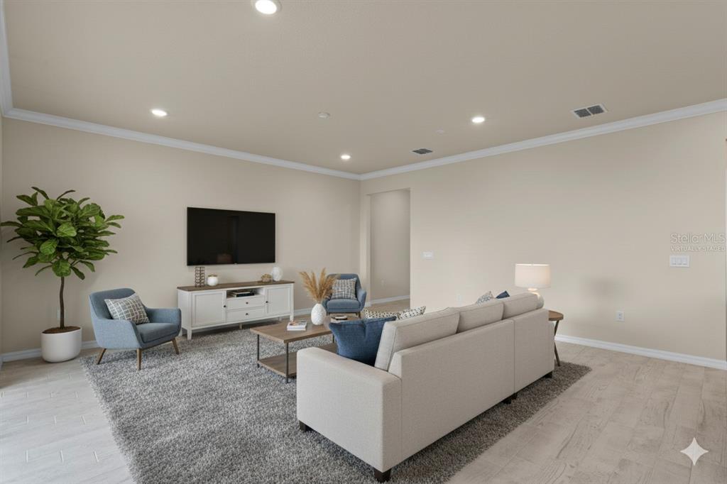 This living room features a beige sofa, two blue armchairs, a television, and a rug — 10245 PARK ESTATES AVENUE, ORLANDO, FL