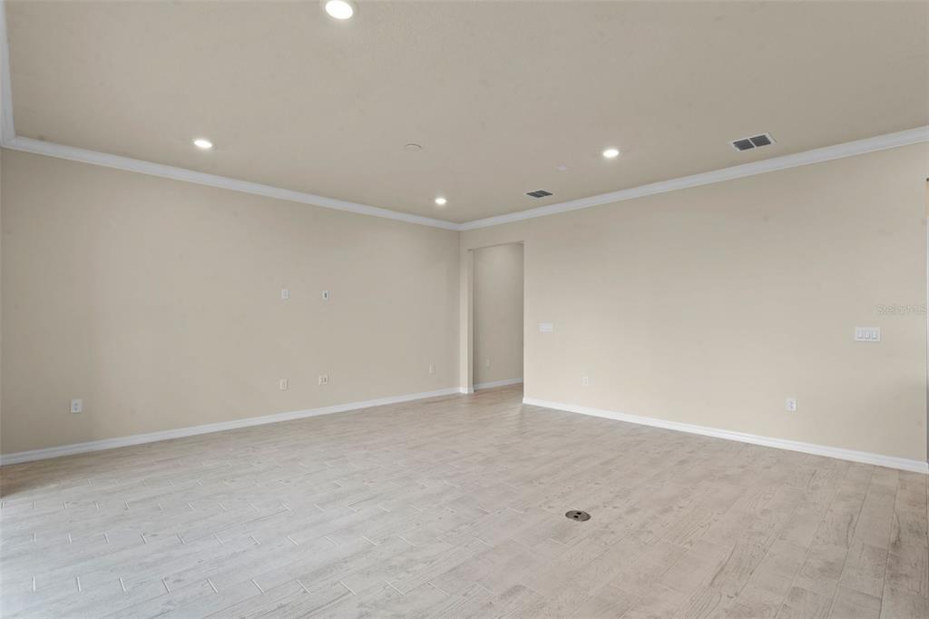 An empty living room features light-colored tile flooring, beige walls, recessed lighting, and a doorway — 10245 PARK ESTATES AVENUE, ORLANDO, FL