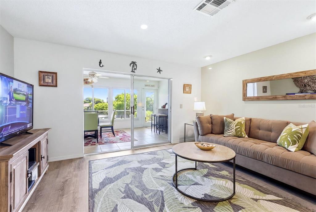 A living room features a brown sofa, a round coffee table, and sliding glass doors — 7003 10TH AVENUE W, BRADENTON, FL