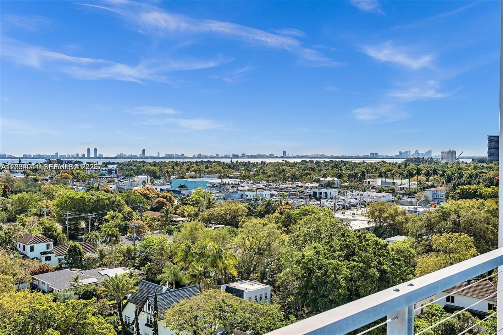 An elevated view shows a lush neighborhood with trees, houses, and a distant skyline — 8101 Biscayne Blvd # 506, Miami FL 33138, MIAMI, FL