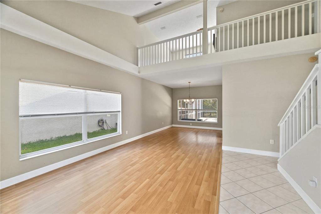 An open living area with wood flooring, high ceilings, a loft balcony, and tiled entryway — 11213 CLAYRIDGE DRIVE, TAMPA, FL