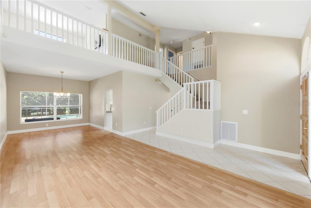 An interior view of a living area with wood flooring, a staircase, and a loft balcony — 11213 CLAYRIDGE DRIVE, TAMPA, FL