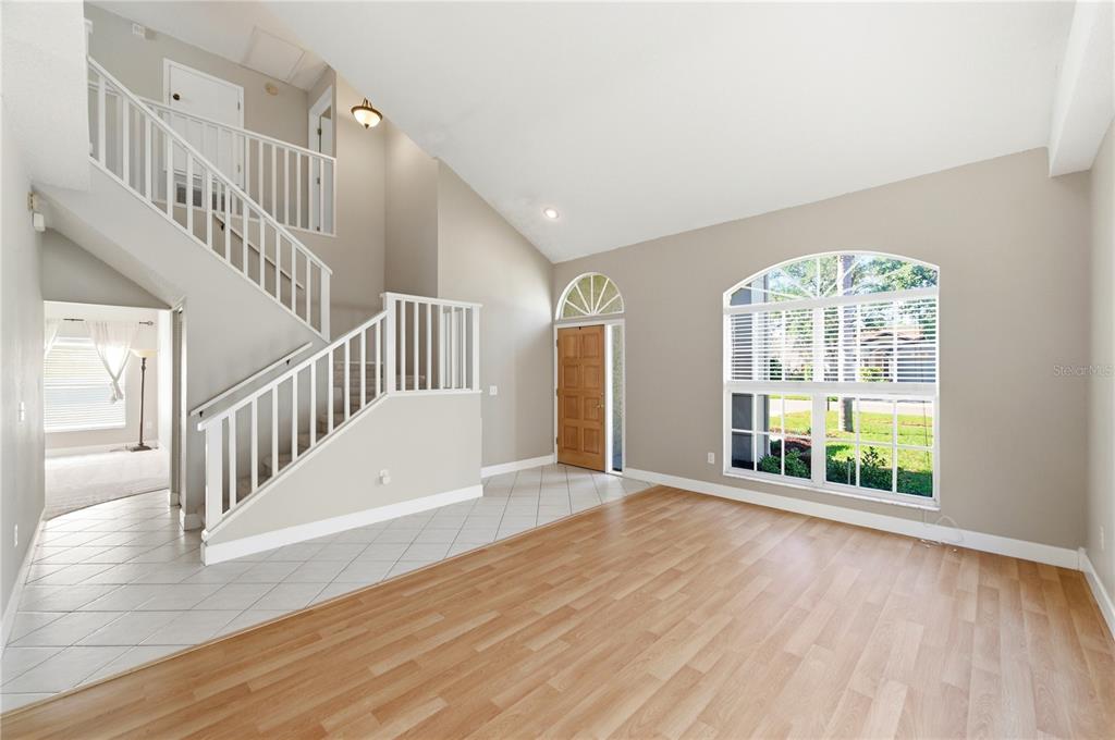 An entryway with tile flooring leads to a staircase and a living room with wood-look floors — 11213 CLAYRIDGE DRIVE, TAMPA, FL