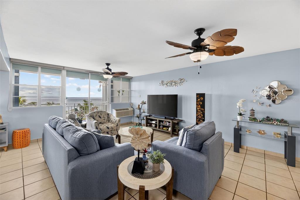A living room with blue walls, tile floors, two ceiling fans, and an ocean view — Route 102 TORRE MARSELLA CONDOMINIUM UNIT 601, CABO ROJO, PR