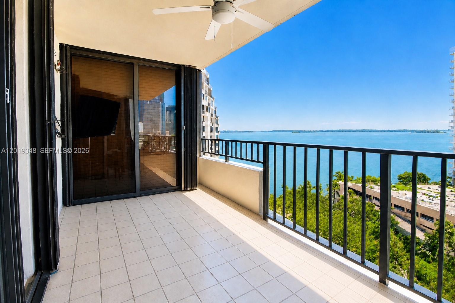 A balcony with white tile flooring overlooks a large body of water and trees — 520 Brickell Key Dr # A1113, Miami FL 33131, MIAMI, FL