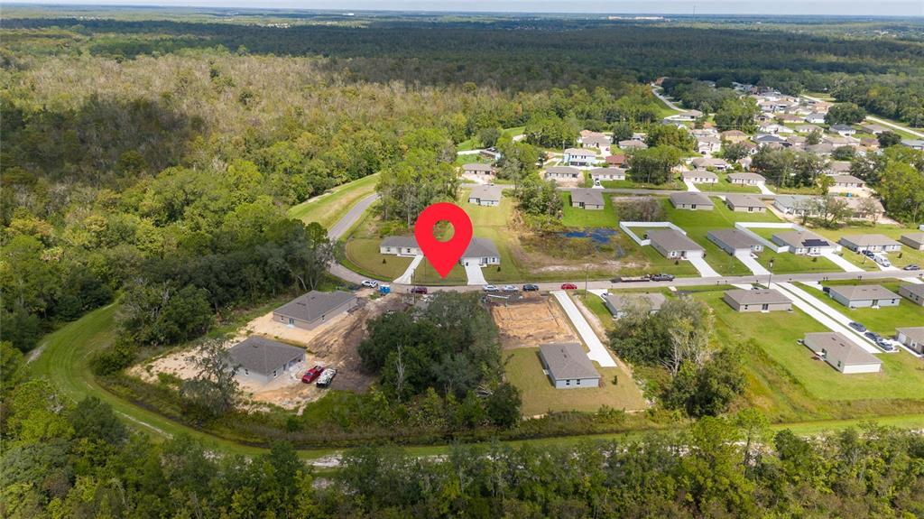 An aerial view shows a residential neighborhood with several houses under construction near a forest — 133 SPARROW COURT, KISSIMMEE, FL