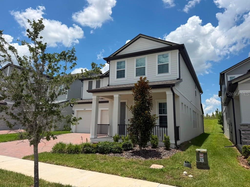 A two-story house with a beige exterior, a front porch, and a paved driveway — 16091 SILVER BROOK WAY, WINTER GARDEN, FL