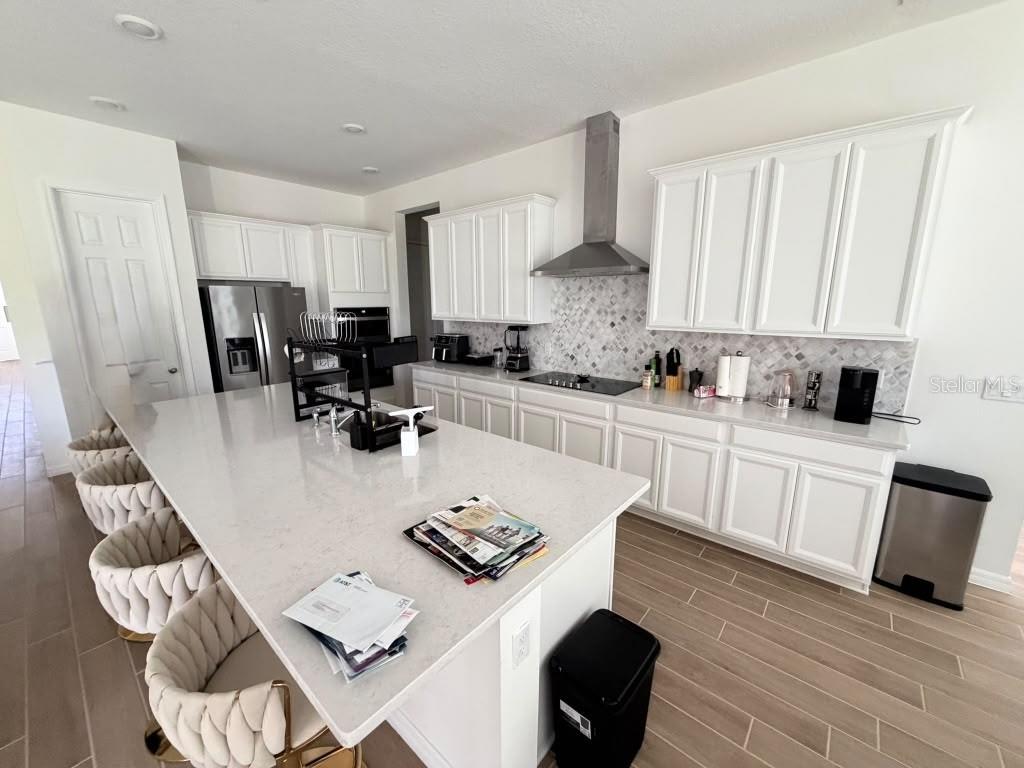 A room with light-colored walls, wood-look tile flooring, several windows, and folding chairs — 16091 SILVER BROOK WAY, WINTER GARDEN, FL