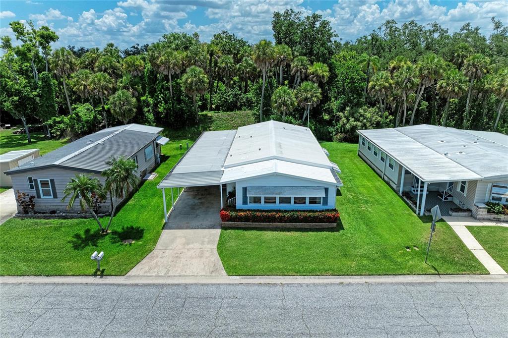 An aerial view shows three manufactured homes with metal roofs and carports along a street — 4543 12TH STREET COURT E, ELLENTON, FL
