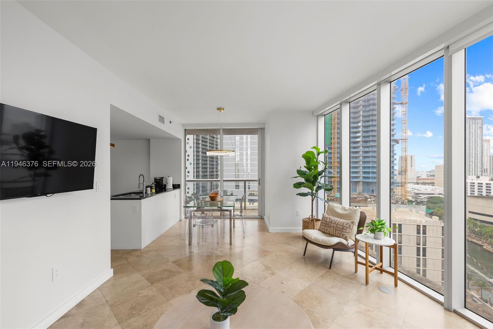A modern apartment living area features tile floors, floor-to-ceiling windows, and an adjacent kitchen — 485 Brickell Ave # 1804, Miami FL 33131, MIAMI, FL