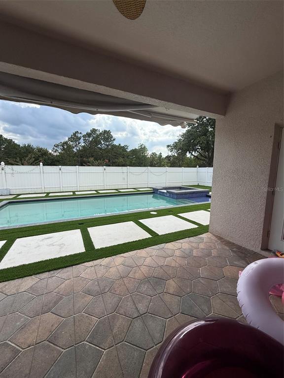 A covered patio overlooks a swimming pool with a spa and a white vinyl fence — 5026 QUALITY TRAIL, ORLANDO, FL