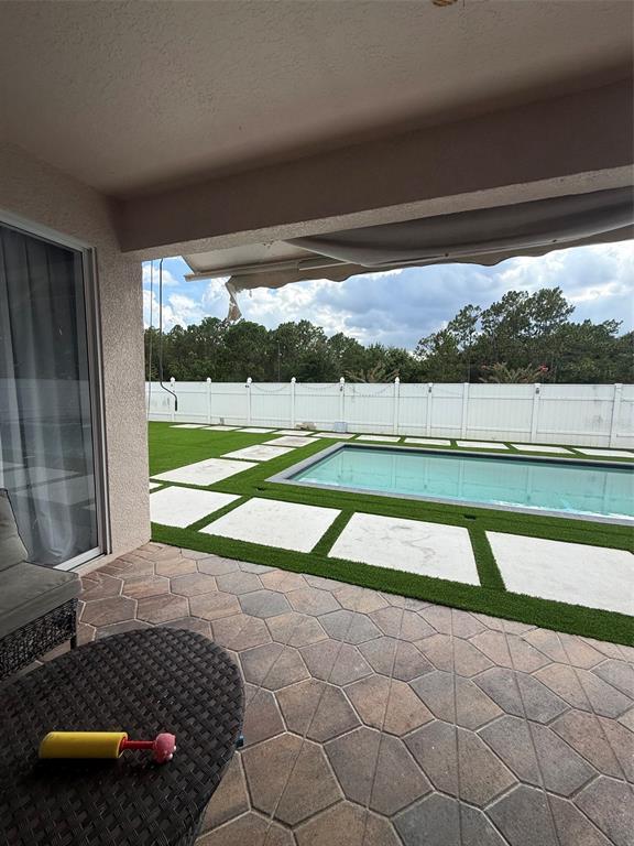 A covered patio overlooks a swimming pool surrounded by artificial turf and concrete pavers — 5026 QUALITY TRAIL, ORLANDO, FL