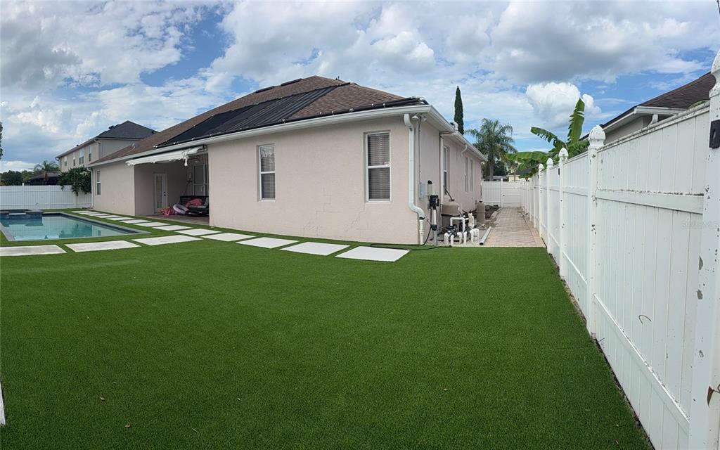 A backyard features a swimming pool, artificial turf, and a white vinyl privacy fence — 5026 QUALITY TRAIL, ORLANDO, FL