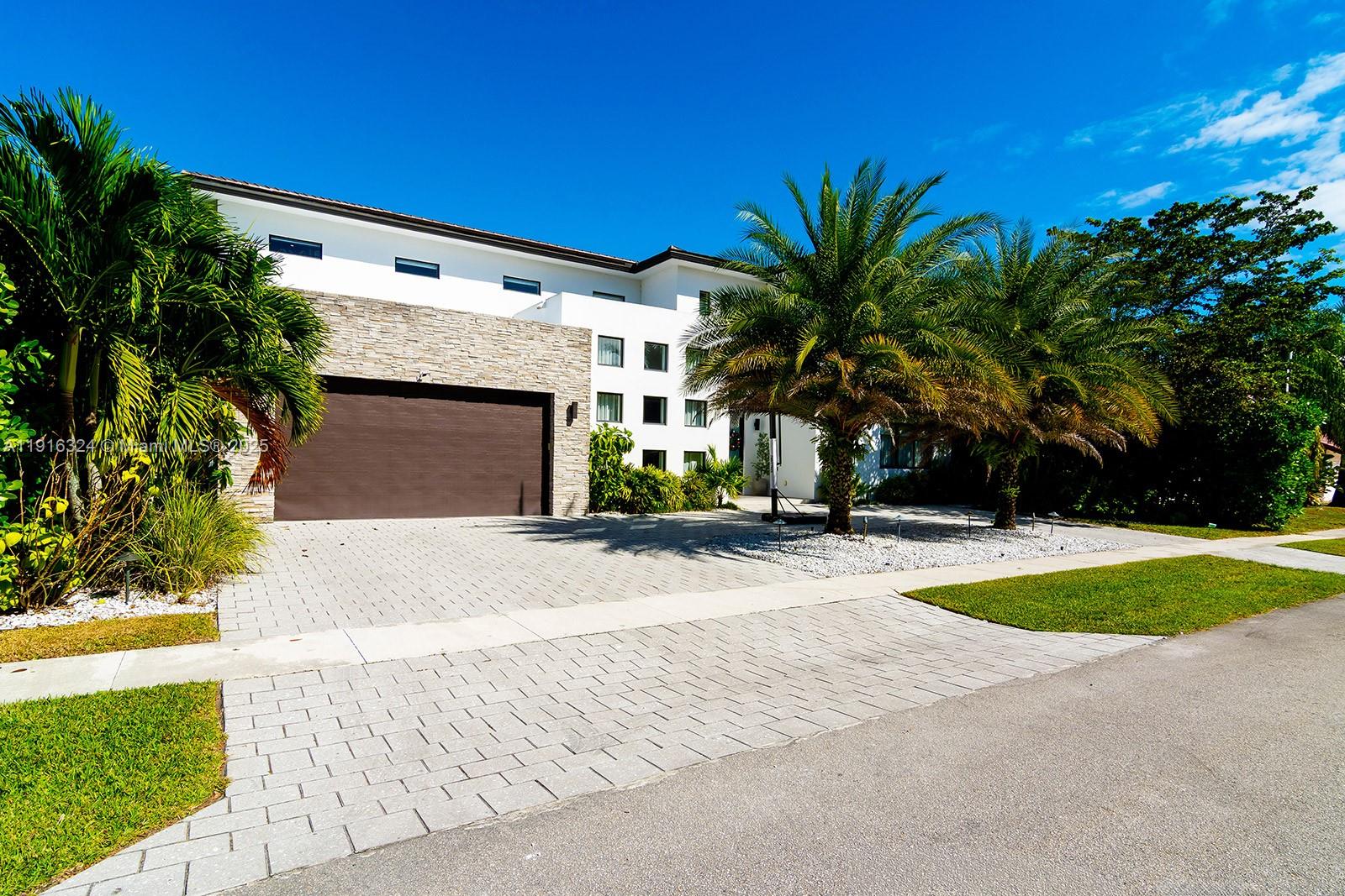 A two-story house with a stone-accented garage and palm trees sits behind a paved driveway — 10151 SW 3rd St, Plantation FL 33324, PLANTATION, FL