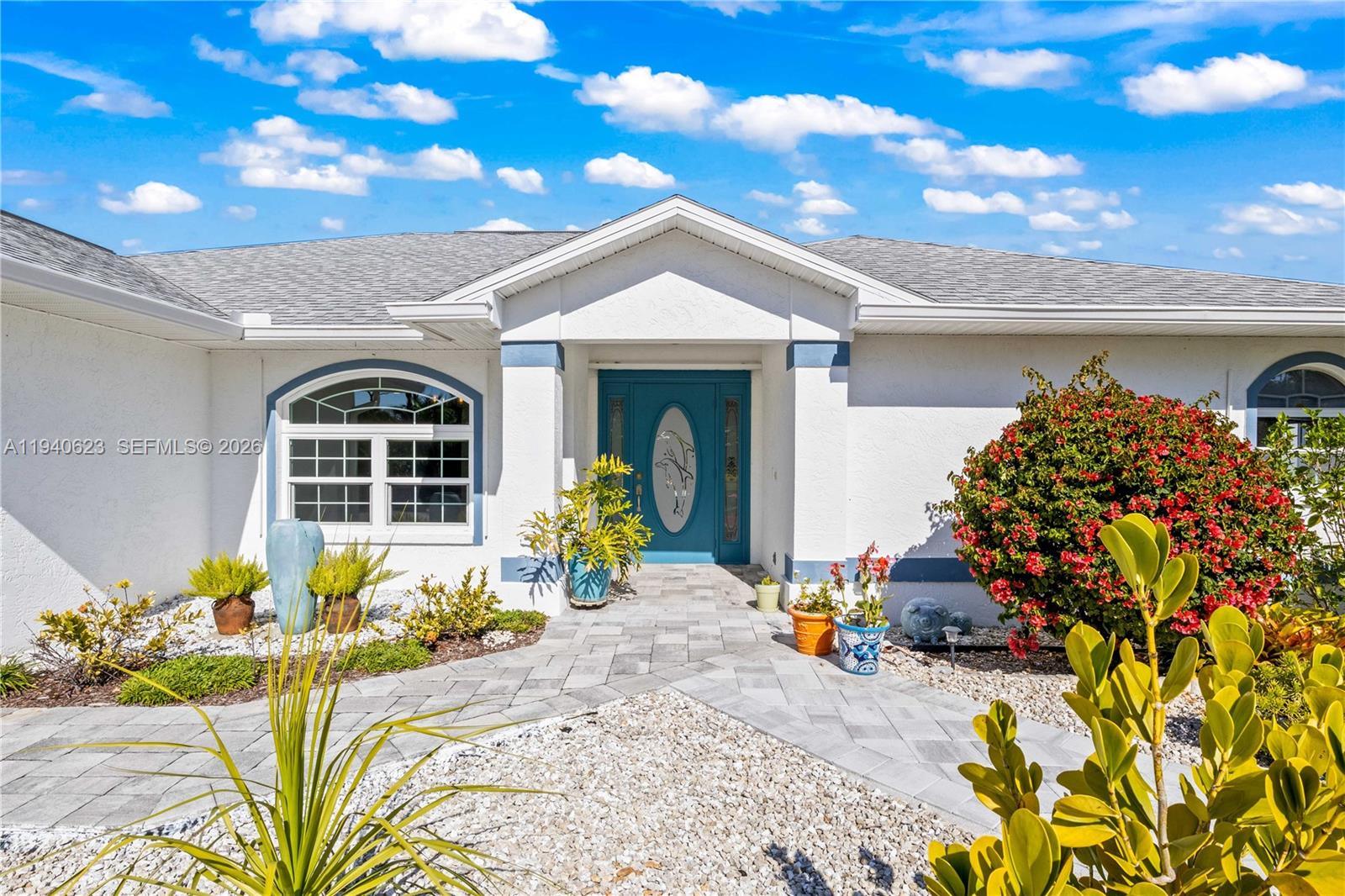 The exterior of a white house features a teal front door and a stone walkway — OTHER CITY - IN THE STATE OF FLORIDA, FL