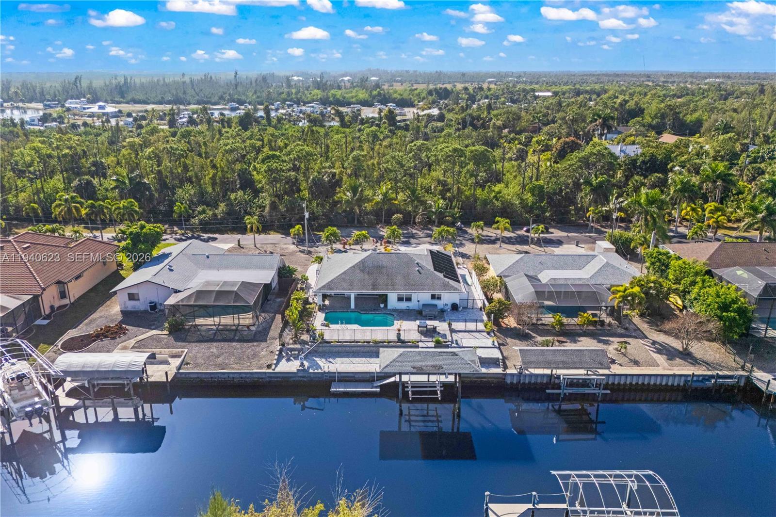 An aerial view shows three waterfront houses with pools, screened lanais, and private boat docks — OTHER CITY - IN THE STATE OF FLORIDA, FL