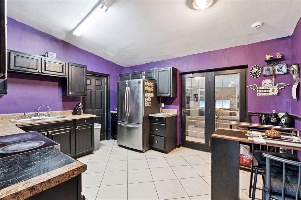 A kitchen features purple walls, black cabinets, stainless steel appliances, and a glass-paned door — 6204 OAKCREST CIRCLE, ORLANDO, FL