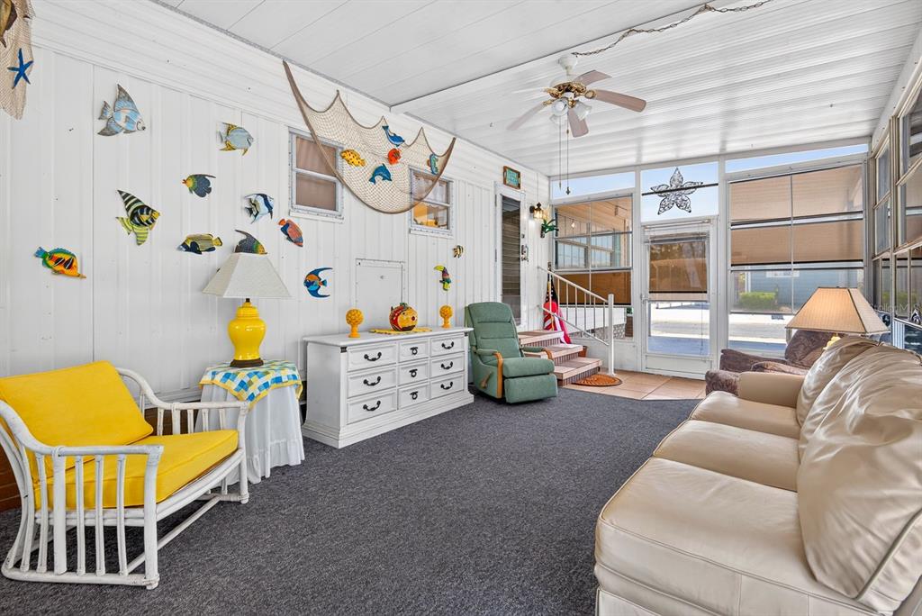 A sunroom features a white dresser, a yellow armchair, a sofa, and nautical wall decor — 37 CABALLO WAY, BRADENTON, FL