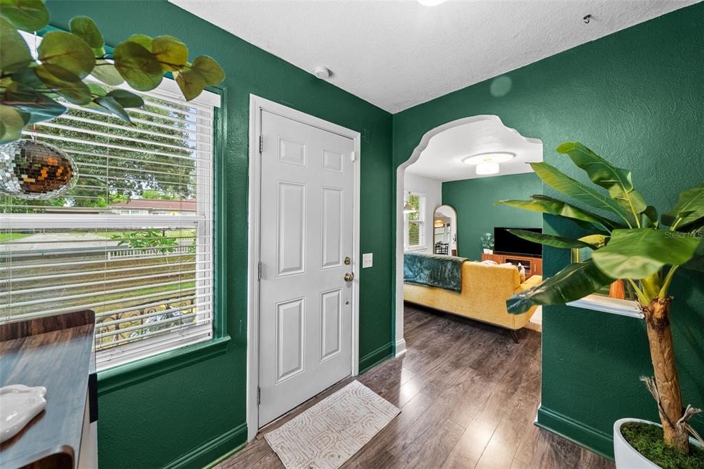 A living room features a green accent wall, yellow sectional sofa, and a wooden media console — 2016 E POWHATAN AVENUE, TAMPA, FL