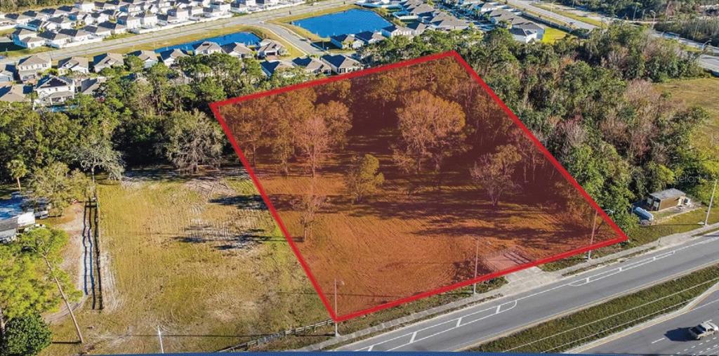 An aerial view shows a rectangular, tree-covered plot of land outlined in red near a road — 6020 US HIGHWAY 17 92 N, DAVENPORT, FL