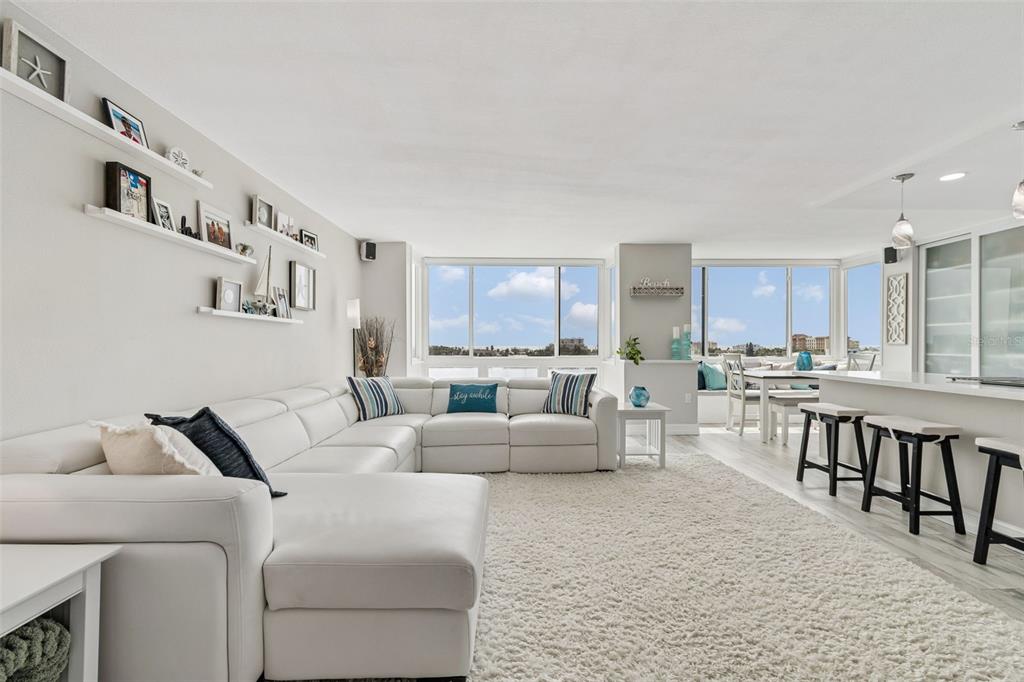 A bright living room features a white sectional sofa, a plush rug, and large windows — 644 ISLAND WAY UNIT 603, CLEARWATER BEACH, FL