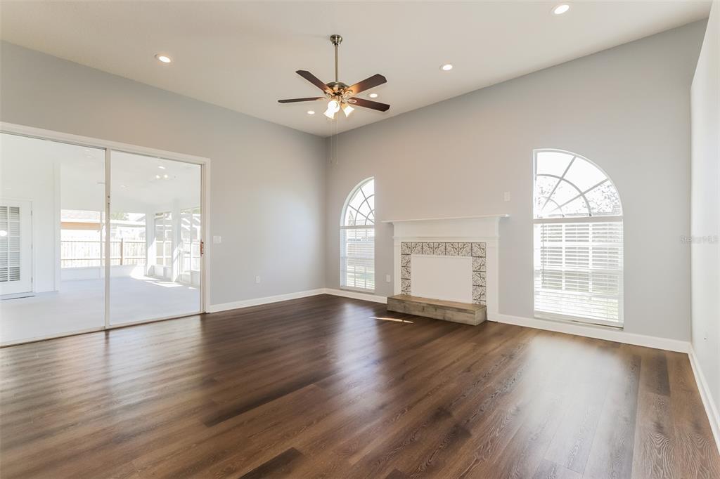 A living room with dark wood floors, a fireplace, and a sliding glass door — 5238 MONTSERRAT COURT, LAKELAND, FL