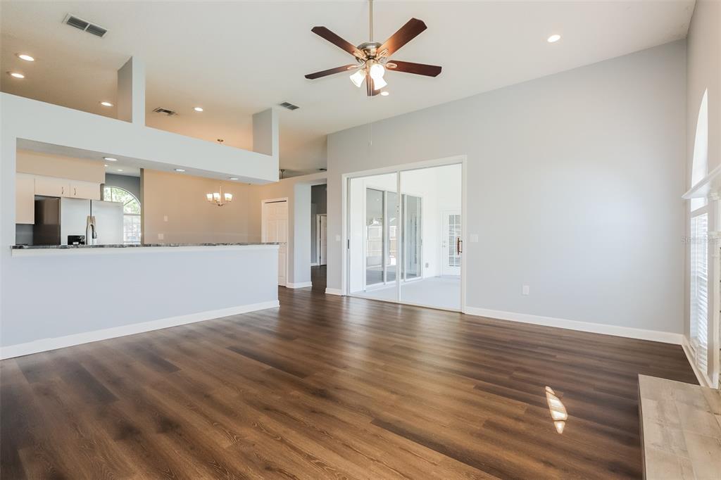 An open-concept living area features dark wood-look flooring, a ceiling fan, and sliding glass doors — 5238 MONTSERRAT COURT, LAKELAND, FL