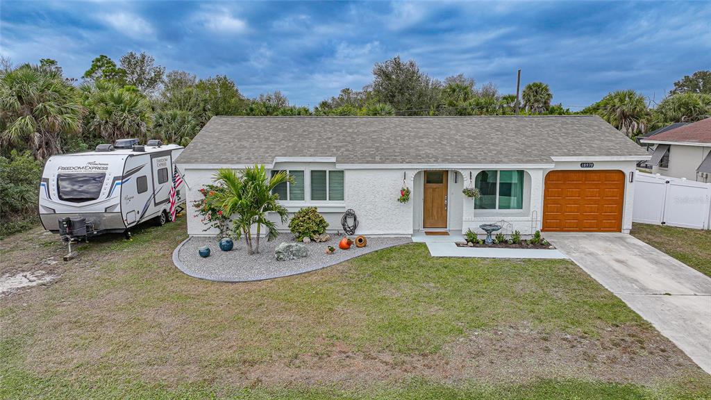 A backyard features a concrete patio with outdoor furniture, a white fence, and a shed — 18970 MCGRATH CIRCLE, PORT CHARLOTTE, FL