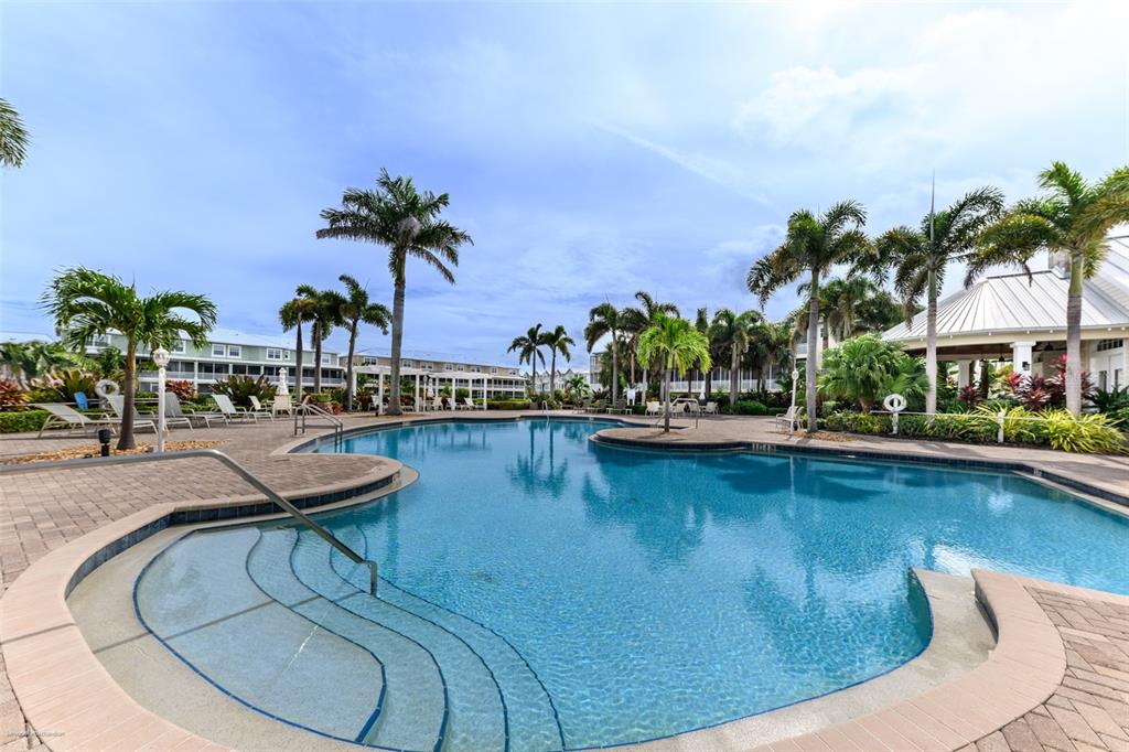 A swimming pool with steps and palm trees surrounded by a paved deck and buildings — 10300 TARPON LANDINGS TERRACE UNIT 4, PLACIDA, FL