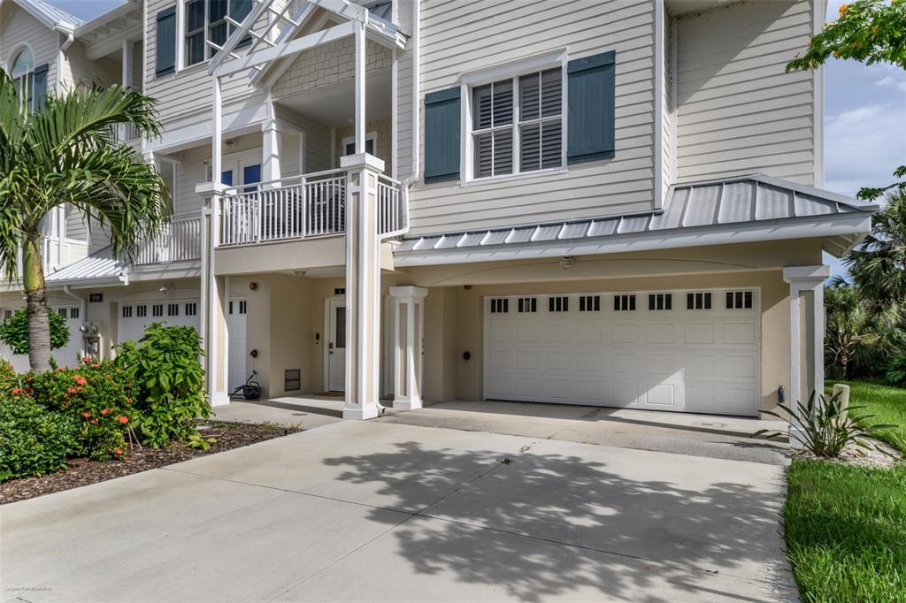 A two-story house exterior with a white garage door, a balcony, and a concrete driveway — 10300 TARPON LANDINGS TERRACE UNIT 4, PLACIDA, FL