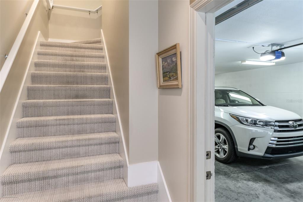 A carpeted staircase leads upward next to an open doorway revealing a garage with a car — 10300 TARPON LANDINGS TERRACE UNIT 4, PLACIDA, FL