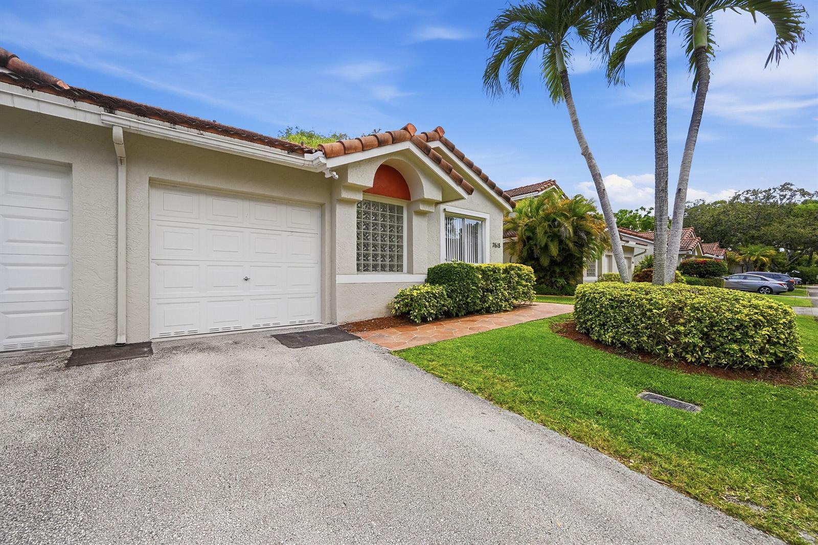 A single-story house with a white garage, glass block window, and palm trees in front — 7618 S Pinewalk Dr S # 132, Margate FL 33063, MARGATE, FL